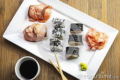 Exposition of sushi rolls on white plate, soya sauce, vasabi and sushi roll. Stock Photo