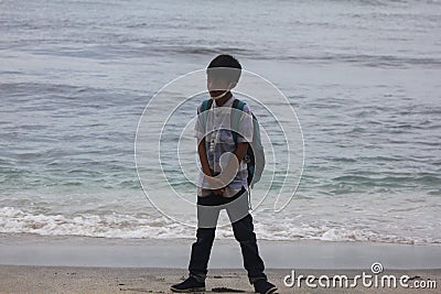 the expression of a child dressed in a blue striped shirt who is enjoying the beach view and wants to play in the sand Stock Photo