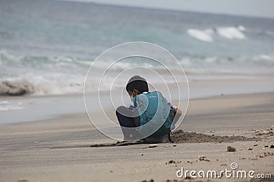 the expression of a child dressed in a blue striped shirt who is enjoying the beach view and wants to play in the sand Stock Photo