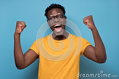 Expressive african american man celebrating success raising his fists up Stock Photo