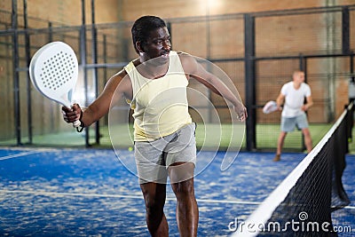 Expressive african american man playing paddle tennis on indoor court Stock Photo