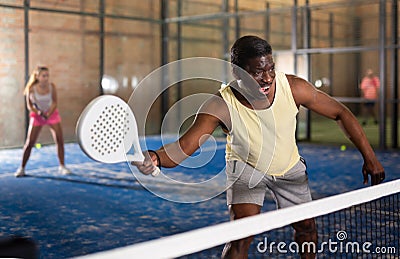 Expressive african american playing paddle ball on closed court Stock Photo