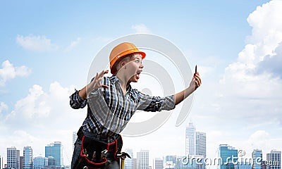 Expressive blonde woman in workwear and hardhat Stock Photo