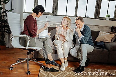 Expressive couple talking to attentive psychotherapist in her cabinet Stock Photo