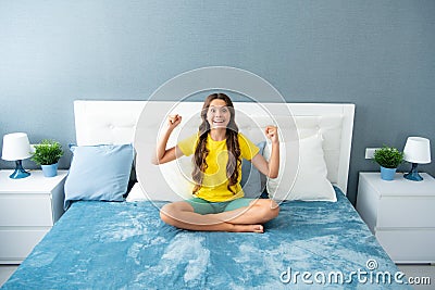 Expressive emotional excited teen girl. Teenager child in bed. Kid relaxing in bedroom interior. Stock Photo