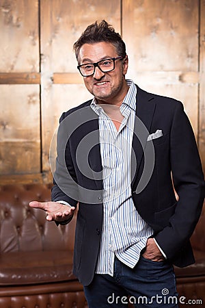 Expressive Frenchman in glasses putting one hand forward and smiling Stock Photo