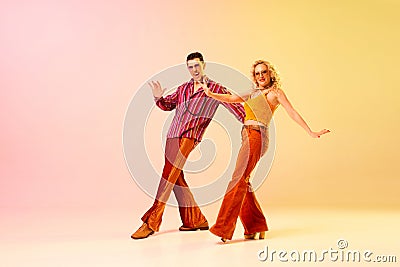 Expressive, talented, emotional couple, man and woman in stylish clothes dancing disco dance against gradient pink Stock Photo