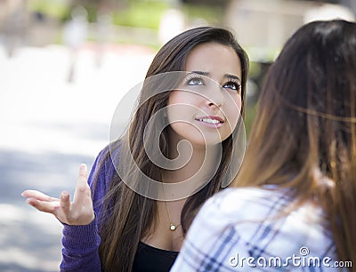 Expressive Young Mixed Race Female Sitting and Talking with Girl Stock Photo