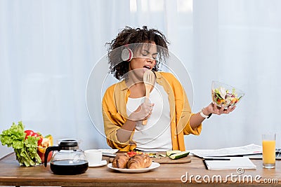 expressive young woman listening music and preparing salad Stock Photo