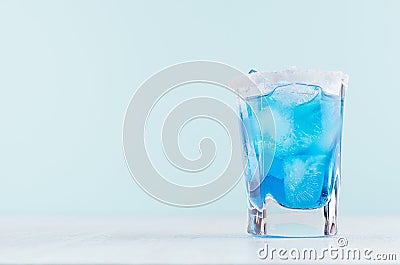 Exquisite blue cocktail for celebration in beach style with blue curacao, ice cube, sugar rim in mint color bar interior on white. Stock Photo