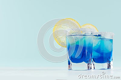 Exquisite blue cocktails for celebration in beach style with blue curacao, ice cube, sugar rim, lemon slice in mint color bar. Stock Photo
