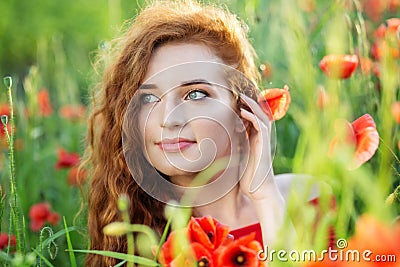 Exquisite young woman smiling in a poppy field. Beautiful make-up. The concept of health, nature, cosmetics and care Stock Photo