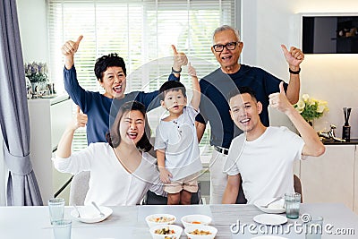 Extended Asian family of three generations having a meal together and showing thumbs up at home with happiness Stock Photo