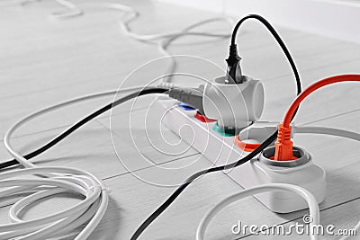 Extension cord with electrical plugs on white laminated floor, closeup Stock Photo