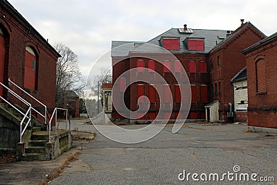 Exterior of boarded up and abandoned brick asylum hospital building with broken windows Stock Photo