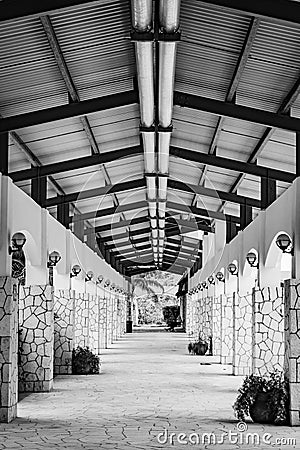 Exterior hallway corridor with high ceiling, lights and fixtures above and along stone wall columns Stock Photo