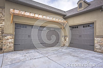 Exterior of a home with view of gray double garage doors and stone wall Stock Photo