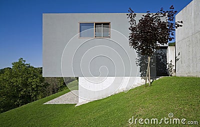 Exterior of a modern colored concrete house. A cube in the middle of the green. Profile view Stock Photo