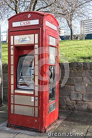 Exterior shot of a telephone kiosk on the pavement with ATM cash point built in. Modern retro design Editorial Stock Photo