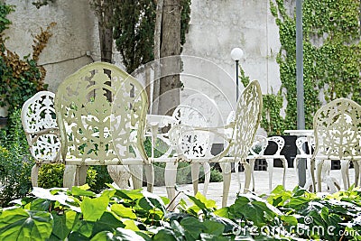 Exterior terrace and garden with white metal classical decoration. Chairs, flowers and empty copy space Stock Photo