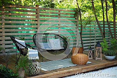 Exterior Terrace with green plants, sofa and lanterns. Cozy space in patio or balcony. Interior Wooden veranda with garden armchai Stock Photo