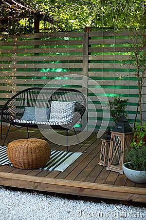 Exterior Terrace with green plants, sofa and lanterns. Cozy space in patio or balcony. Interior Wooden veranda with garden armchai Stock Photo