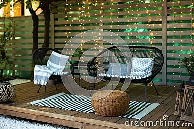 Exterior Terrace with green plants, sofa and lanterns. Cozy space in patio or balcony. Interior Wooden veranda with garden armchai Stock Photo