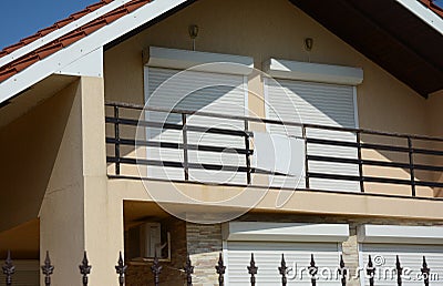 A exterior view of large attic, loft windows closed with pvc motorized window roller shutters leading to the open balcony of a Stock Photo