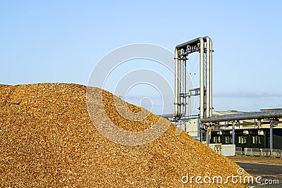 Modern biomass cogeneration power plant equipment with a mountain of wood chips in the foreground Stock Photo