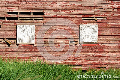 Exterior wall on old wood red barn with boarded up windows Stock Photo