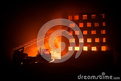 extinguish the fire of a private house at night. Toy fire truck with long ladder and burning building at night. Fire alarm concept Stock Photo
