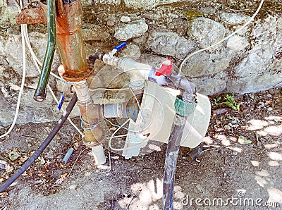 Extraction of water from underground sources. white plastic bottles are connected to the valves for pumping water Stock Photo
