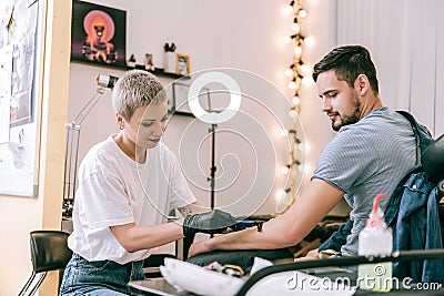 Extraordinary short-haired tattoo master shaving off hair from hand Stock Photo