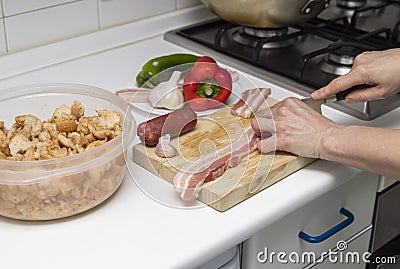 Extremadura crumbs, traditional dish. Hands cutting bacon, ingredients breadcrumbs, bacon, red and green pepper, crumbs, chorizo, Stock Photo