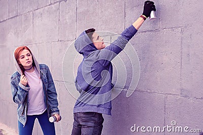 Extremal dark-haired guy using bottle of spray paints Stock Photo