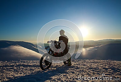 Extreme biker on sport motorcycle on winter snow mountain on sky Stock Photo