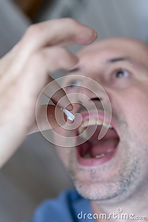 Extreme closeup man face taking white pill, mouth view swallowing pills, illness. man take medicine,open mouth and bring medicine Stock Photo