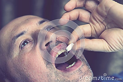 Extreme closeup man face taking white pill, mouth view swallowing pills, illness. man take medicine,open mouth and bring Stock Photo