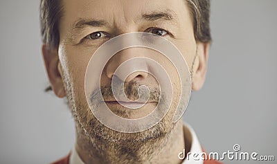 Closeup portrait of serious senior man looking at camera on grey studio background Stock Photo