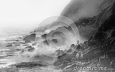 Extreme Crazy Fishing in stormy conditions at Porth Nanven in Cornwall. Waves and sea spray backlit by sun Stock Photo