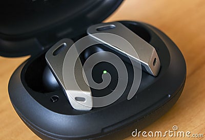 Extreme shallow depth of field, Macro shot of Futuristic design small wireless headphones or earphone lie on a green wooden Stock Photo