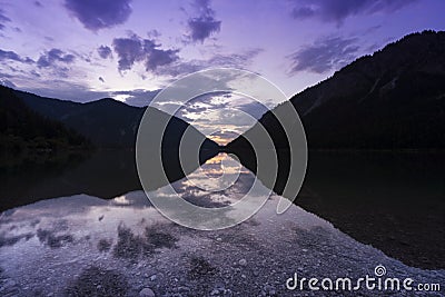 extremely clear water of lake plansee in the tyrolean alps with mountain sillhoutte in the morning Stock Photo