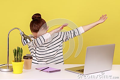 Extremely excited woman office worker sitting at workplace with laptop, showing dab dance gesture. Stock Photo