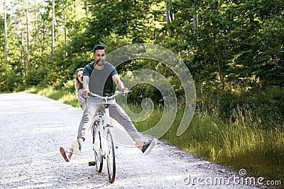 Exuberant couple sharing a bicycle in rural landscape Stock Photo