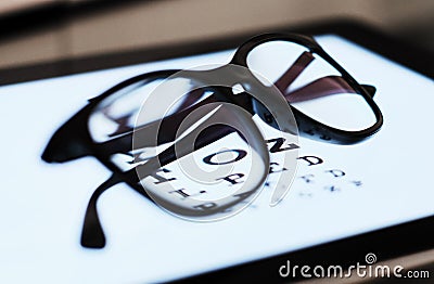 Eye chart on tablet and the glass with E Standard Logarithm Eyesight Tablet on top of the light screen Stock Photo