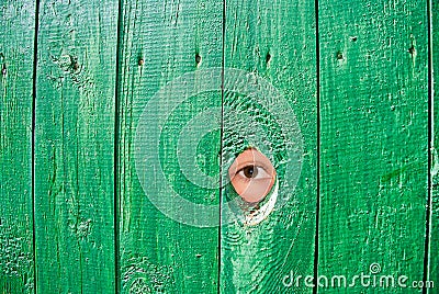 Eye in a hole in fence Stock Photo