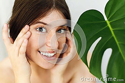 Eye Skin Care and Treatment. Portrait of beautiful young happy woman holding hands at eyes skin at green palm leaf. Girl enjoying Stock Photo