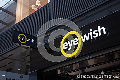 Eye Wish Opticien store, with illuminated shop logo. Editorial Stock Photo