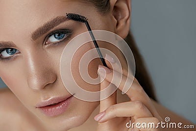 Eyebrow makeup. Woman brushing brows with gel brush closeup Stock Photo