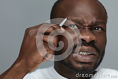 Eyebrow Shape Grooming For Male. Closeup Of Model Removing Brow Hair With Tweezers. Stock Photo